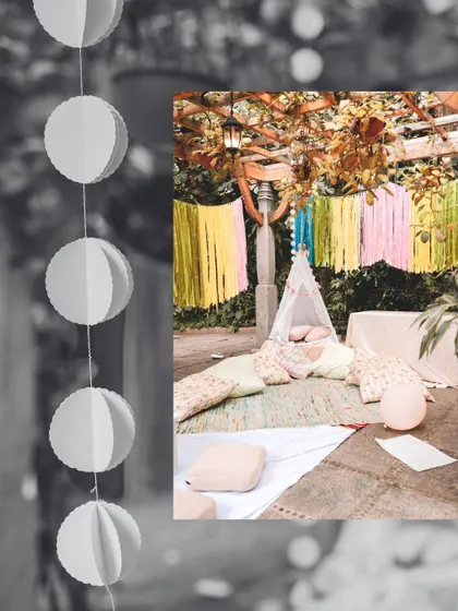 A black and white filtered image showing the details of a boho picnic, including hanging decorations and a cozy teepee tent.