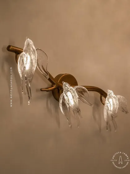 A close-up of our bird-themed wall sconce. Three delicate glass birds are mounted on a small rose-gold branch, providing a soft, ambient light. It's a charming accent piece that complements the larger chandeliers in the series or stands beautifully on its own.