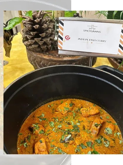 A delicious and comforting Indian Fish Curry, garnished with fresh cilantro, served hot in a modern cooking pot.