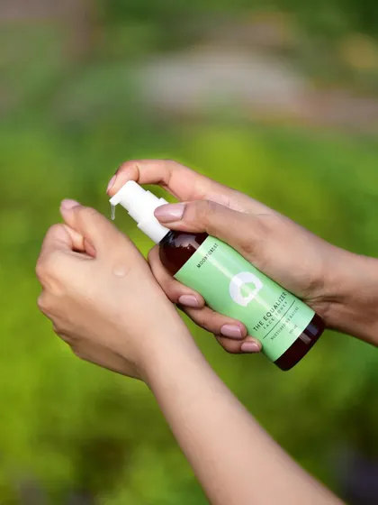 An in-use lifestyle shot of Moon Forest's face toner being applied to the wrist. This demonstrates the product's texture and application in a natural, outdoor setting.