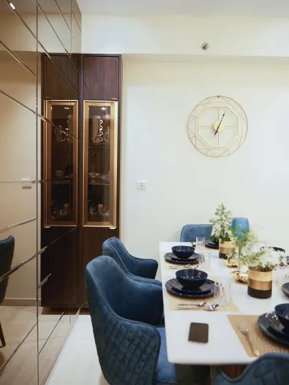 A dining area in a Lodha Complex apartment, showcasing a marble table, blue velvet chairs, and a mirrored wall that enhances the sense of space.