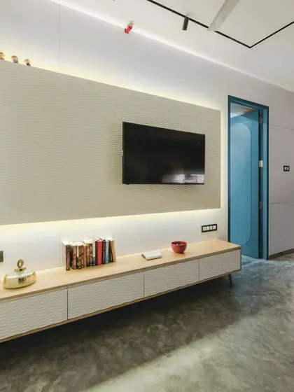 The entertainment unit is a sleek combination of rubberwood and a white wave board panel, providing stylish storage and a textured backdrop for the television.