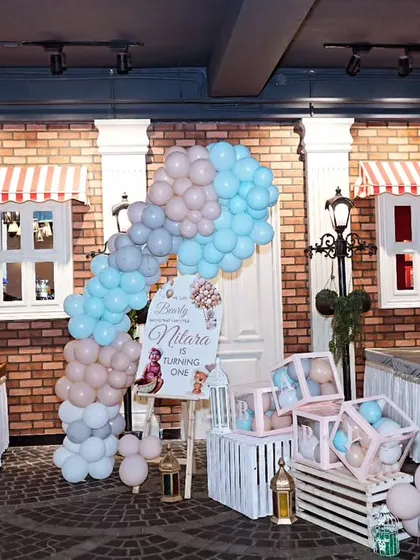A charming party setup with a brick wall backdrop, pastel balloon arch, and themed props, showcasing a "We Can Bearly Wait" baby shower or birthday theme.