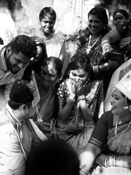 A black and white candid of the wedding rituals, with the family looking on with smiles and happy tears. It captures the communal joy and emotion of the ceremony.