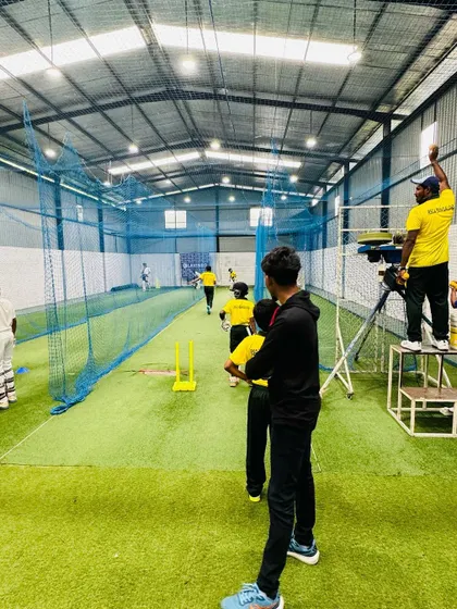 Inside the nets, our coaches use modern tools like video analysis to provide immediate feedback. Here, a coach records a session from an elevated position for a better technical review.