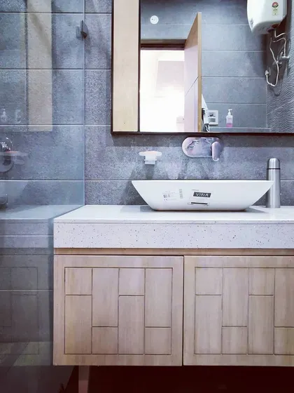 The bathroom design for Villa 9/21B features textured grey wall tiles and a custom wooden vanity. We focus on creating functional yet beautiful private spaces, using a combination of durable materials and modern fixtures.