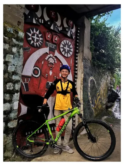 A rider posing with his bike in front of a traditionally carved wooden gate in an Angami Naga village. Our tours are as much about cultural immersion as they are about cycling.