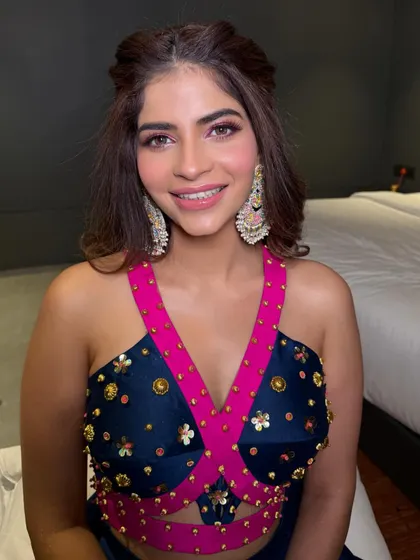 The client looks happy and ready to celebrate in her colorful outfit, with a hairstyle that is both stylish and comfortable for a day of festivities.