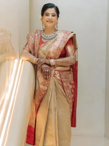 The mother of the groom looking elegant in a custom beige and gold saree. The saree is embellished with dabka and sitara work and paired with a hand-embroidered bandhani dupatta.