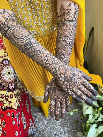 A beautiful shot of the bridal henna against a vibrant yellow outfit. The design's complexity and elegance are clearly visible.