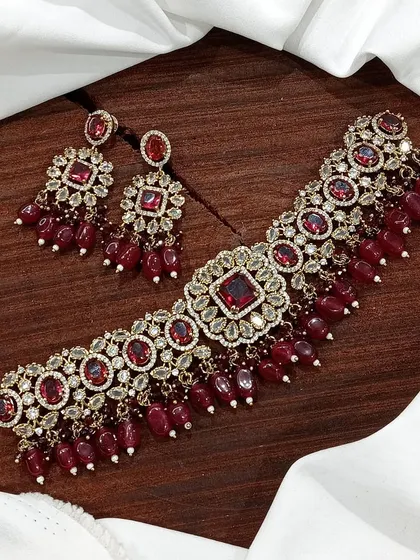 A versatile choker set available in multiple colors including white pearl, ruby, emerald, and pastel pink. The design features a central square motif with hanging beads, making it a popular choice for various festive occasions.
