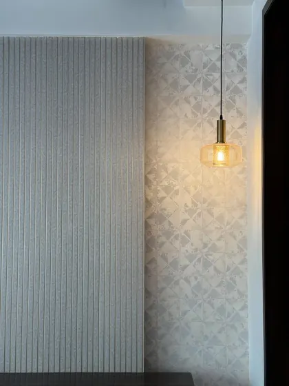 Texture is key to adding depth. This statement wall combines a vertically fluted panel with a subtly patterned wallpaper, creating a sophisticated play of lines and patterns, all highlighted by a single pendant light.