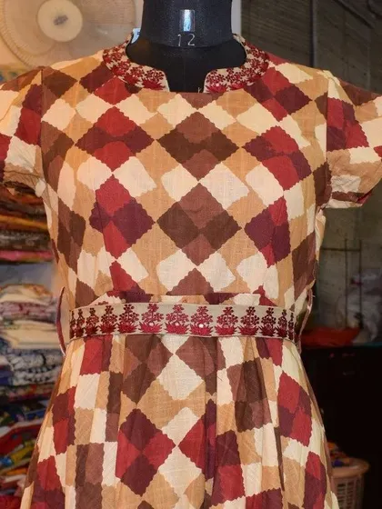 The warm, earthy tones in this diamond-patterned cotton kurti are perfect for the transition from summer to autumn. The delicate embroidery on the waist and neckline adds a touch of festive detail.