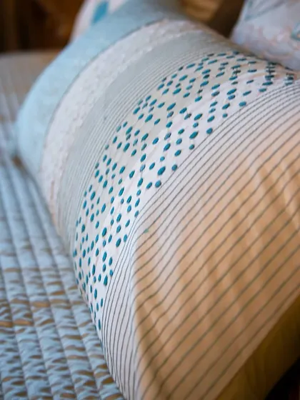 A close-up of a cushion from my summer collection, featuring a mix of stripes and dotted patterns in a light, airy teal. This piece is perfect for adding a fresh touch to your decor.