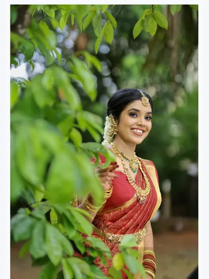 A lovely candid portrait of a bride peeking through lush green leaves, her natural smile lighting up the frame.