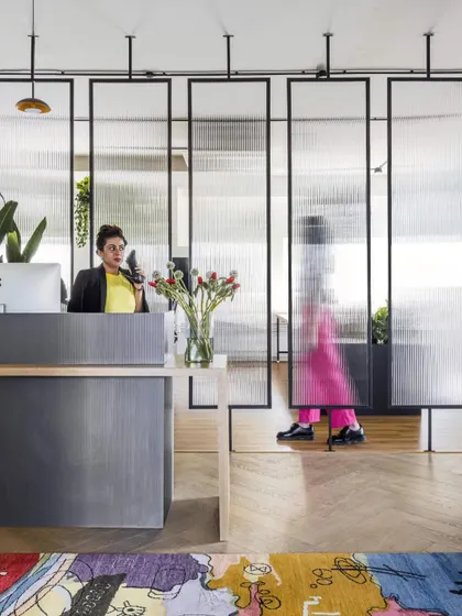 A closer look at the reception desk and the custom-designed glass partitions at the LWYD office. The design balances industrial elements with soft textures and vibrant colors to create a unique brand statement right at the entrance.