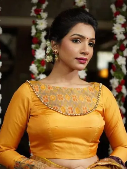 A yellow long-sleeved blouse with a sheer neckline panel and beadwork.