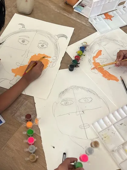 An overhead view of our self-portrait session. We provide a range of skin-toned paints and colors to ensure every child can represent themselves authentically.