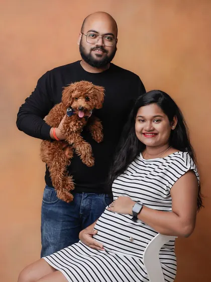 A simple and classic studio maternity portrait of a couple with their pet dog. This shows how we can include your furry friends in this special milestone.