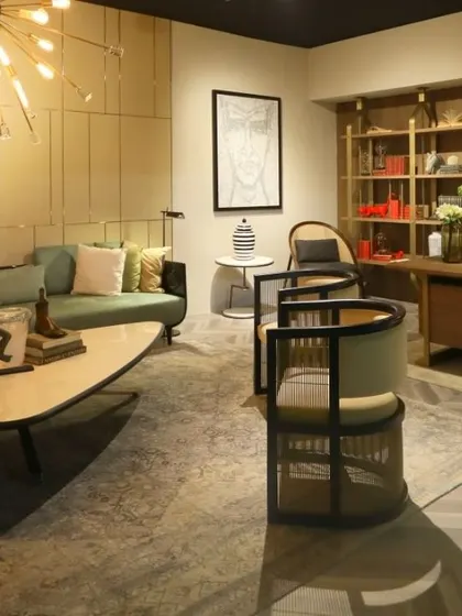 This lounge space, designed for an exhibition, features wall panelling with clean, geometric lines in a soft, neutral tone. It creates a calm and contemporary backdrop for the living and home office areas.