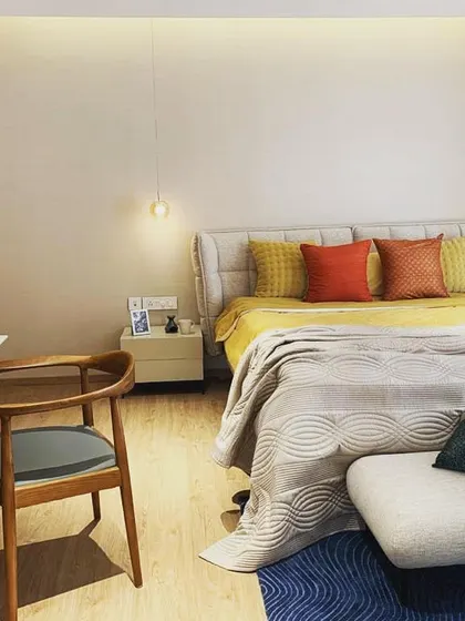 This mockup bedroom demonstrates a cozy and inviting design using a palette of warm neutrals, wood tones, and pops of yellow and orange. Layered textiles and soft lighting contribute to the comfortable ambiance.