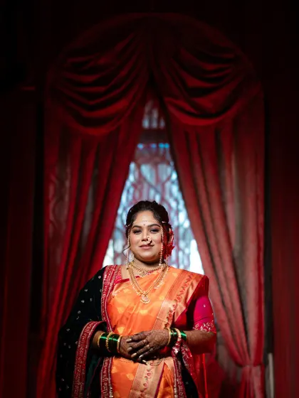 A beautiful portrait of the bride framed by a dramatic red curtain. The lighting and composition give this photo a regal and theatrical quality.