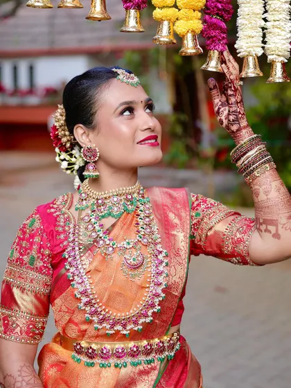 A stunning South Indian bride, with the deep stain of her mehndi visible as she reaches for floral decorations.