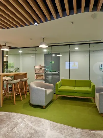 Another view of the green lounge, which serves as a waiting area near the reception. The slatted wood ceiling adds warmth and texture.