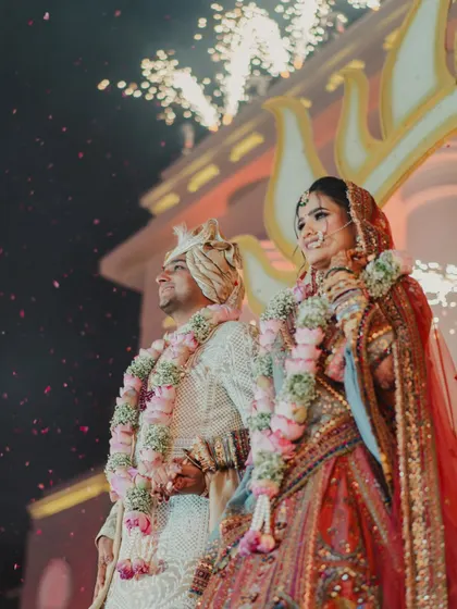 Love, laughter, and happily ever after. A beautiful shot of the couple during their varmala ceremony, with fireworks lighting up the sky behind them.