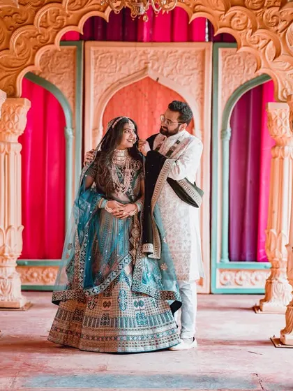 A full-length portrait of a couple in a grand, palatial setting. Their intricate outfits and the stunning architecture create a truly regal pre-wedding photo.