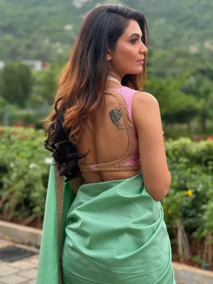 The back view of Shwetha's blouse, featuring a deep, open-back design with delicate gold border work.