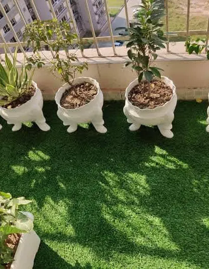 A playful and charming balcony with quirky leg planters on a bed of artificial grass. It's all about adding personality to your green space.