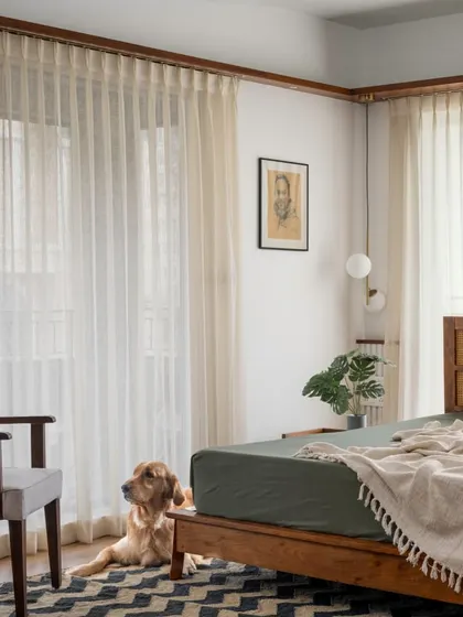 Max, the family pet, enjoys the serene atmosphere of the 'Vasudhalayah' master bedroom. The room is filled with natural light, and the earthy green and wood tones create a calming retreat.