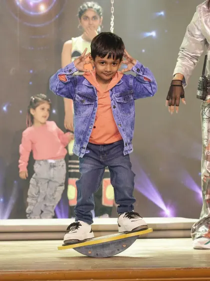 Balance is fundamental. This young performer confidently uses a balance board on stage, demonstrating the improved motor skills and physical control gained through our specialized training activities.
