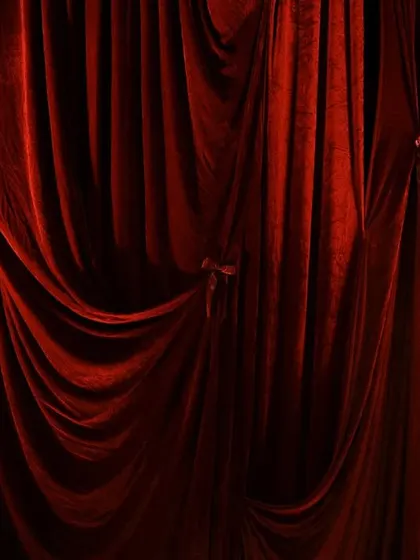 A full frame of the rich, red velvet drapes. The fabric is gathered and tied with satin ribbons, adding a simple yet elegant detail to the overall design.