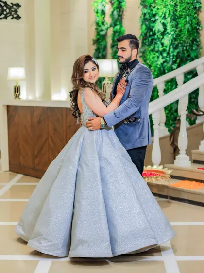 A grand couple portrait on a beautiful white staircase. The bride's voluminous silver gown and the groom's stylish suit create a modern fairytale look.
