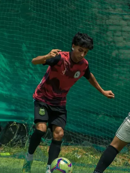 A player dribbles past a defender near the corner flag.