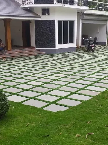 This image shows our precision in laying stone pavers with grass inlays for a large driveway. The result is a clean, geometric pattern that is both functional and aesthetically pleasing, leading up to the home's porch.