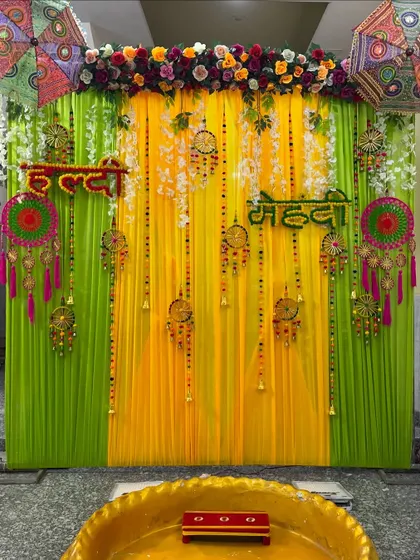This photo shows the full Haldi-Mehendi setup with the 'urli' seating in the front. The decor is designed to create a complete and immersive experience.
