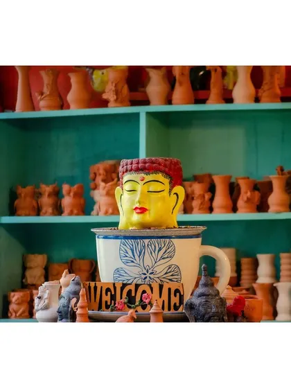 A glimpse of our eclectic decor, featuring a large Buddha head planter and shelves of terracotta pottery, creating a peaceful, artistic vibe.