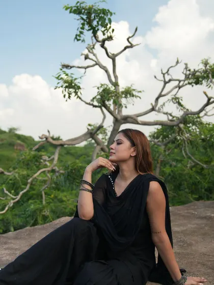 A profile shot of the model in the black suit, with a unique tree framing the background.