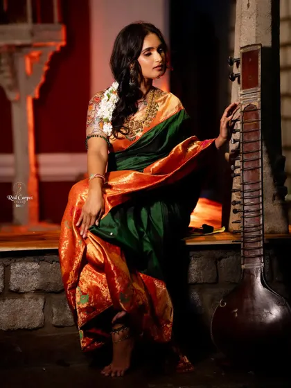 Kaavya Shastry posing with a sitar, looking like a classical muse in the green and orange silk saree.
