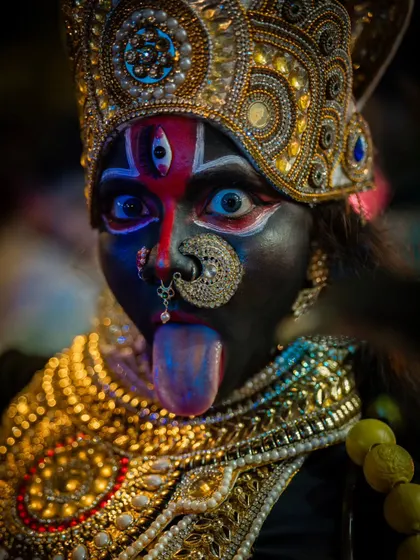 A direct, powerful portrait of a performer. The intense gaze, detailed makeup, and traditional jewelry tell a story of devotion and power.