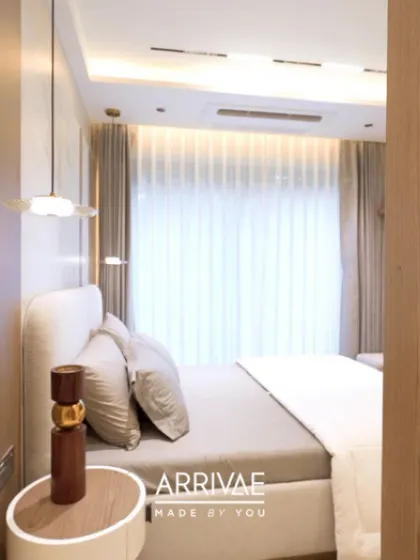 A bright and airy bedroom with a simple, elegant design. The focus is on soft textures, a neutral color palette, and delicate pendant lighting to create a calm and restful space.