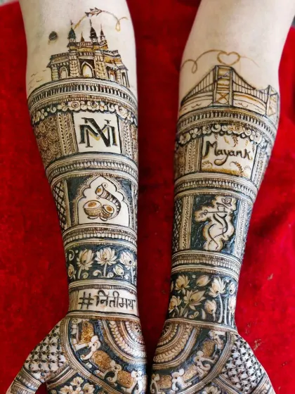 A detailed view of the skyline mehendi, showing the Gateway of India and Bandra-Worli Sea Link with the couple's initials and names.