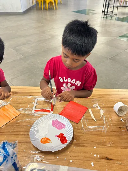 A little boy carefully painting a frame at our DIY art station.