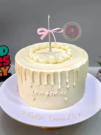A simple and elegant vintage cake with a white chocolate drip and a single candle for a 25th birthday.