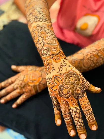 This floral henna design includes the groom's name, "Aamir," beautifully written on the palm.
