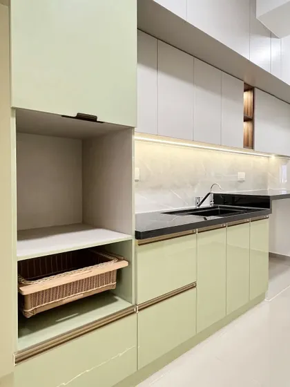 This shot shows the clever integration of a wicker basket for storage within the green cabinetry, blending natural textures with modern finishes.