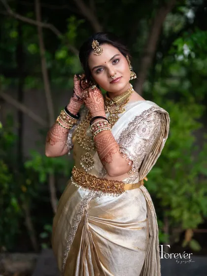 Adjusting the final details. This shot captures the bride in her full traditional attire, with makeup that enhances her beauty and completes her regal look.